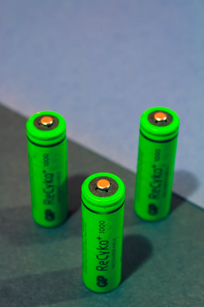 services-05 Close-up of three green rechargeable batteries standing on a colored surface.